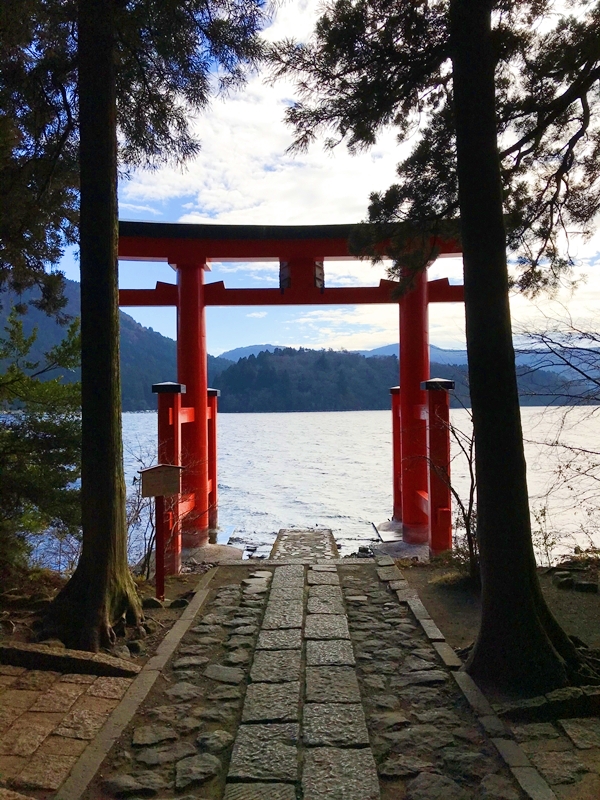 芦ノ湖に立つ箱根神社の平和の鳥居と、その背景に広がる静かな湖面と山並み